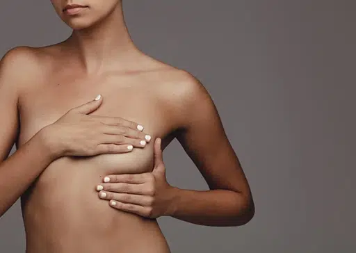 A woman posing with her hands on her breasts, demonstrating breast implant massage techniques.